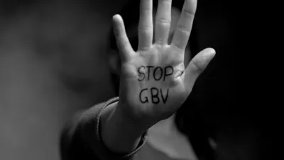 Black and white photo focused on a person's hand with the words "Stop GBV" written on it. GBV stands for "gender-based violence."