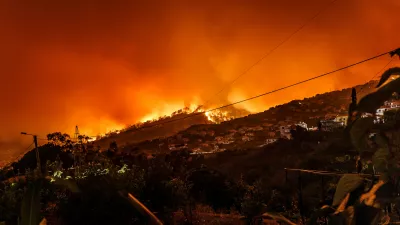 a wildfire blazing over a tree-covered hill
