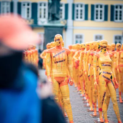 an art installation depicting bodies wrapped in yellow tape with slogans protesting against domestic violence