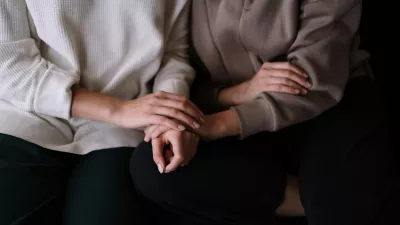 women clasp hands offering each other support